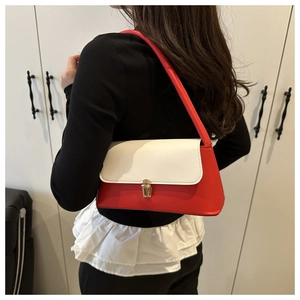 Detail view of red and white shoulder bag with golden buckle worn by a model