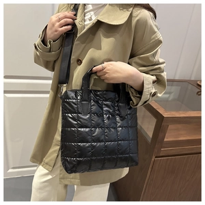 Close-up of black quilted nylon bucket bag featuring soft texture and wide shoulder strap