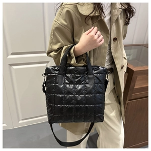 Close-up of black quilted puffer tote bag featuring textured lattice stitching and strap