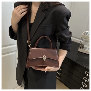 Detail of a brown trapezoid handbag with gold metal lock buckle and fine leather texture