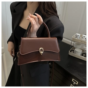 Detail of dark brown retro crossbody bag featuring a golden oval clasp and smooth leather