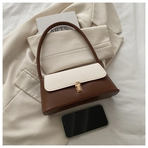 Détail d'un sac à bandoulière marron et crème avec boucle dorée sur tissu blanc