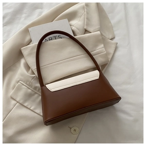 Vue détaillée du sac à bandoulière bicolore chic sur un blazer avec une esthétique française