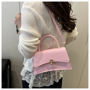 Detail view of pink leather crossbody bag with gold metal twist lock and top handle