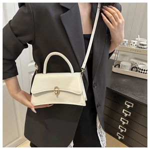 Close-up of cream crossbody bag featuring golden double-ring twist lock and leather handle