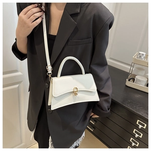 Close-up of white leather crossbody bag with gold double-ring lock on black blazer