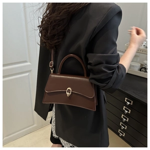 Detailed view of a brown vintage leather tote bag with gold ring clasp and top handle