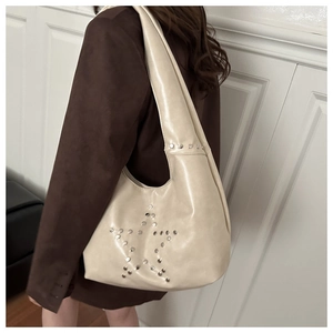 Detail of cream shoulder bag featuring silver star stud patterns and PU leather texture