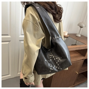 Detail of black PU leather shoulder bag with silver star rivets and wide strap