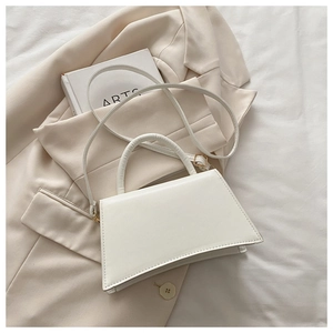 Close-up of minimalist white trapezoid handbag with premium matte leather and metal lock