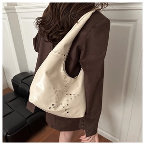 Detail view of cream oversized hobo bag featuring silver studded star pattern decorations