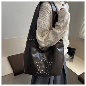 Detail of dark brown leather hobo bag with vintage silver star rivet decorations