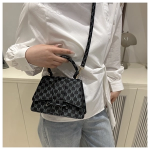 On-body shot of a chic M-pattern crossbody bag with top handle and adjustable strap