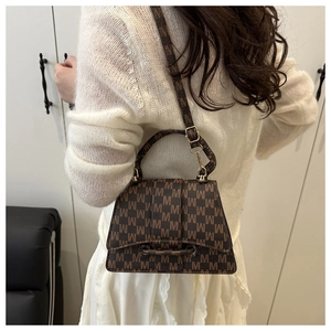 Detailed view of brown letter print handbag with a trapezoidal flap and leather handle