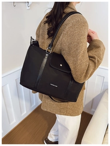 Detail of black tote bag with leather straps and front pocket for casual commute