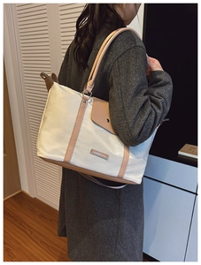 Side view of a large beige and brown contrast shoulder tote bag worn by a model