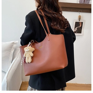 Detail of caramel tote bag with golden logo and cute bear charm in lifestyle setting