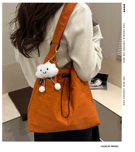 Detail of orange nylon shoulder bag with drawstring closure and soft cloud keychain