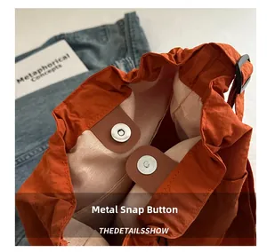 Details des silbernen Magnetverschlusses an oranger Nylontasche mit Leder-Patch