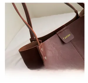Detailed close-up of dark brown leather tote bag with lychee texture and gold logo
