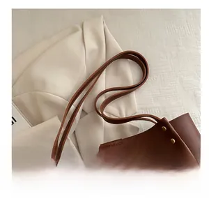 Close-up of brown tote bag featuring litchi grain texture and gold rivet details