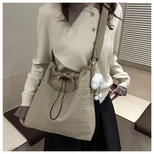 Detail of khaki drawstring tote bag with plush charm and adjustable wide shoulder strap