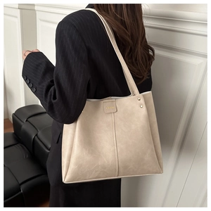 Detail of soft cream tote bag showing gold rivets and vertical stitching details