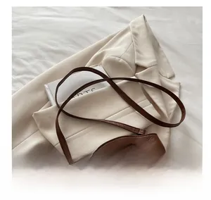 Detailed view of two-tone quilted leather crossbody bag on white blazer