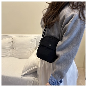 Detail of black nylon crossbody bag with metal M logo and adjustable thin strap