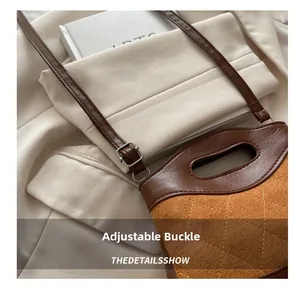 Detail of adjustable metal buckle and contrast color stitching on retro leather handbag
