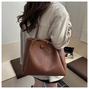 Detail of a brown large capacity tote bag with reinforced rivets and soft leather texture