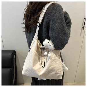 Detail of cream canvas tote bag with drawstring closure and cute cloud plush charm