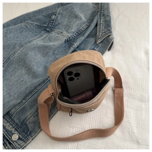 Interior view showing khaki crossbody bag holding a smartphone and a lipstick