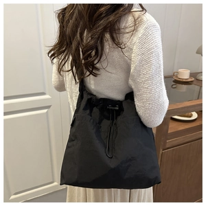 Black drawstring tote bag made of high-density nylon fabric shown on a model's shoulder