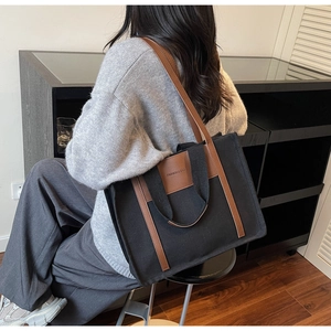 Detail of canvas tote bag with brown leather handles and dual shoulder straps