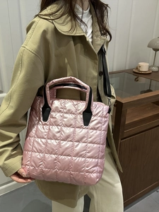 Chic pink quilted puffer bucket bag with black handles and adjustable crossbody strap