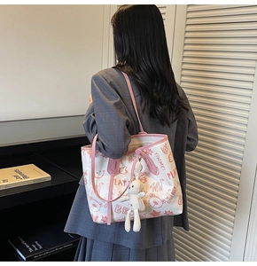 Detailed back view of a white tote bag with pink cartoon graffiti and a bunny charm accessory