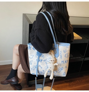 Close-up of cream canvas tote bag with blue graffiti patterns and a cute bunny charm