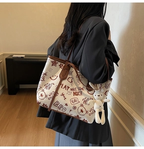 Detailed side view of canvas tote bag with graffiti prints and a plush rabbit charm
