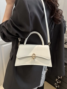 Elegant cream white trapezoid crossbody bag with gold buckle and top handle on black blazer