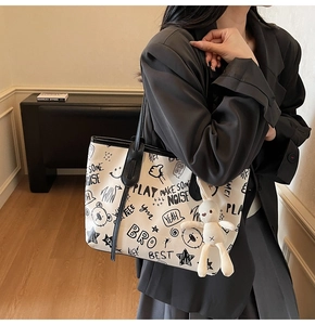Detail of white graffiti tote bag with black letters, art patterns and rabbit charm
