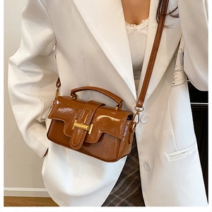Détail d'un mini sac brillant caramel avec boucle en métal doré et bandoulière en cuir