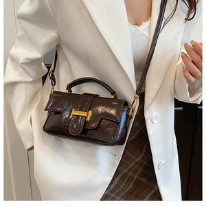Détail d'un sac à main en cuir marron foncé avec une boucle en métal doré élégante