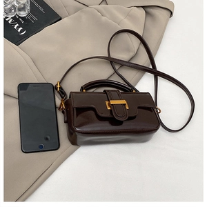 Détail d'un sac à main vintage marron foncé en cuir huilé avec boucle dorée et bandoulière