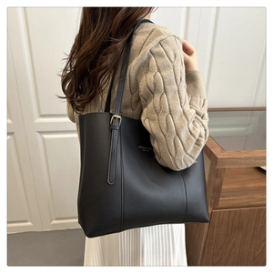 Model wearing a large black matte leather tote bag with gold lettering for daily commute