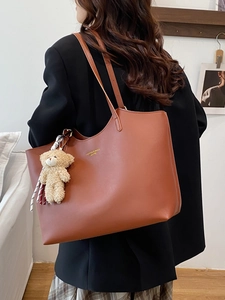Brown leather tote bag with shoulder strap and cute plush bear charm for daily commute