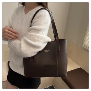 Detail of dark brown leather tote bag with gold lettering and long shoulder straps