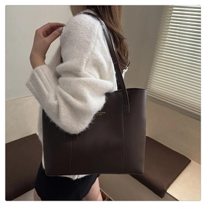 Detail of dark brown leather tote bag with gold lettering and slim shoulder strap
