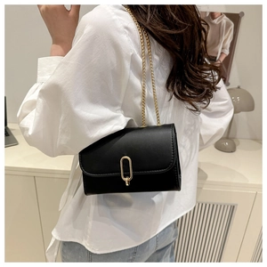 Détail d'un sac bandoulière noir avec boucle dorée en U et fine bandoulière en chaîne