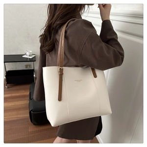 Close-up of a white leather tote bag with brown straps and fashion text print